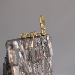 Gold stud earrings on shiny mineral surface, 18ct gold earrings with priness cut diamonds and hand-carved texture resembling mineral stritations