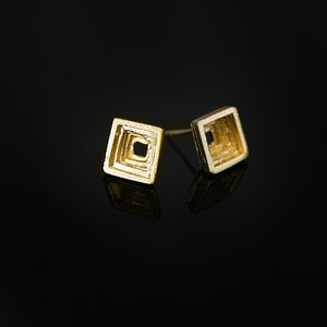 Cavetto architectural stud earrings in fire-textured 18kt gold, side view.