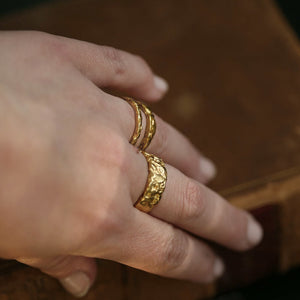 Liquid Aurum unisex statement rings set in 18kt yellow gold and raw, hand-forged texture, on hand.